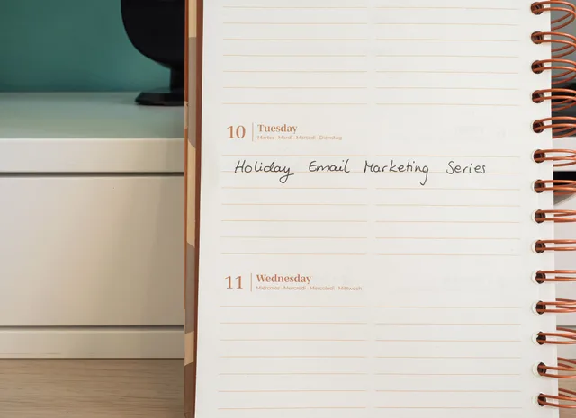 Planner open on a desk with handwritten 'Holiday Email Marketing Series' note. How to Benchmark Healthcare Email Marketing