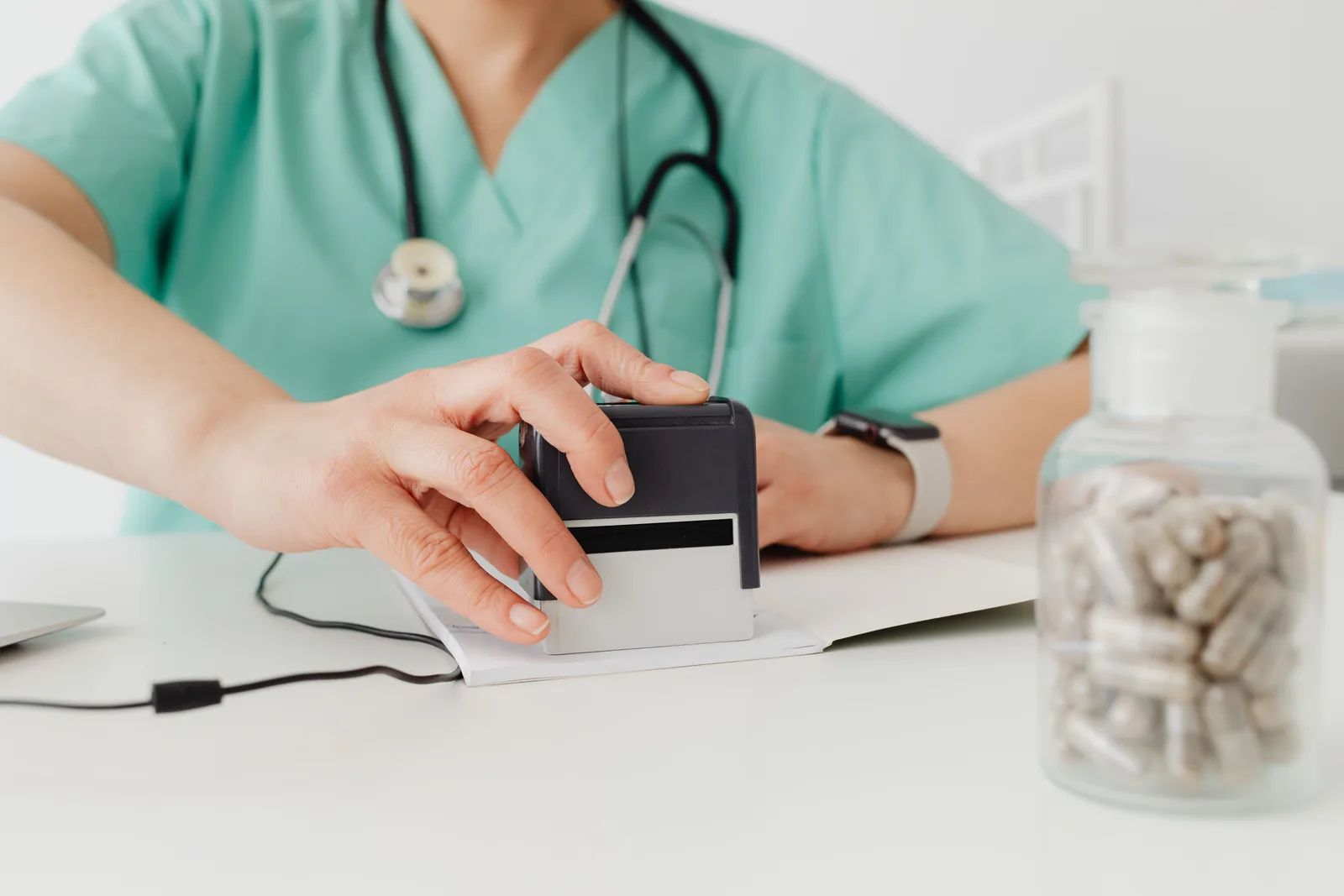 Close-up of a doctor stamping a prescription with a bottle of pills on a desk. Which Healthcare Marketing Compliance Trends Matter