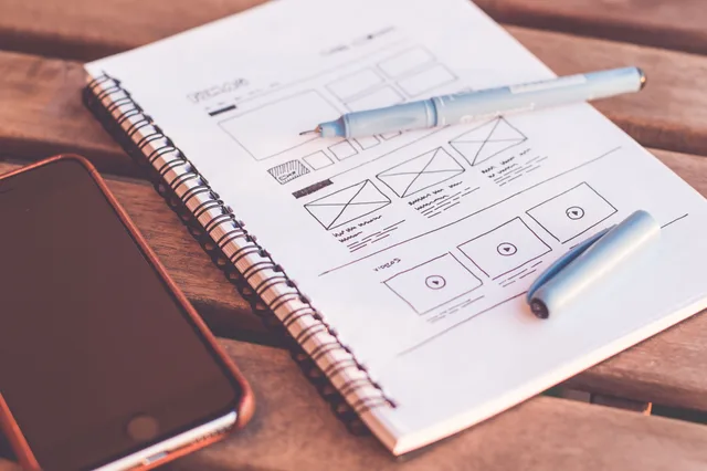 Close-up of a notebook with wireframe sketches and a smartphone on a wooden desk. Healthcare SEO Page Designs Worth Copying for Every Service Line