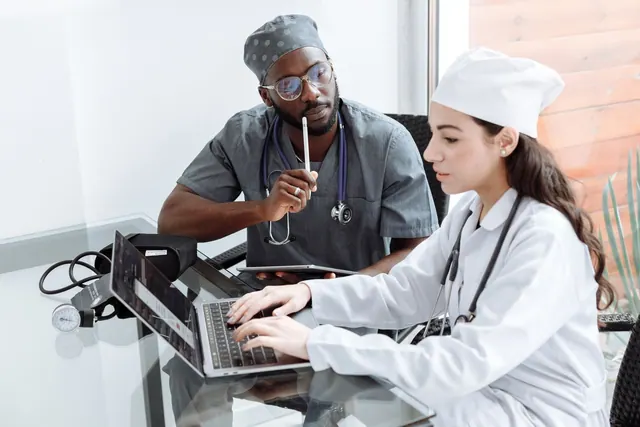 Two doctors discuss patient diagnosis using laptop in hospital office. Healthcare Social Media Guide for Business