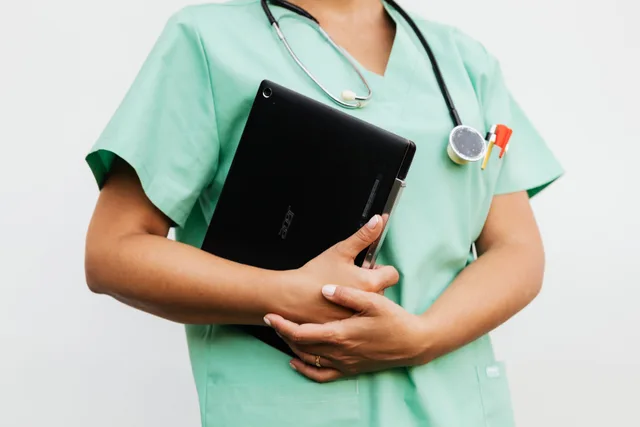 Close-up of a nurse in green scrubs holding a tablet and stethoscope, symbolizing modern healthcare. How to Improve Healthcare Email Marketing: Tactics, Rules and a Test Method